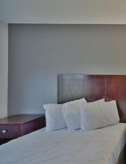 Neatly made bed with white bedsheets in motel room